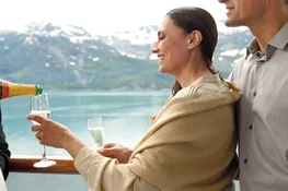 People enjoying the view on the deck of an Alaska Cruise ship and drinking champagne