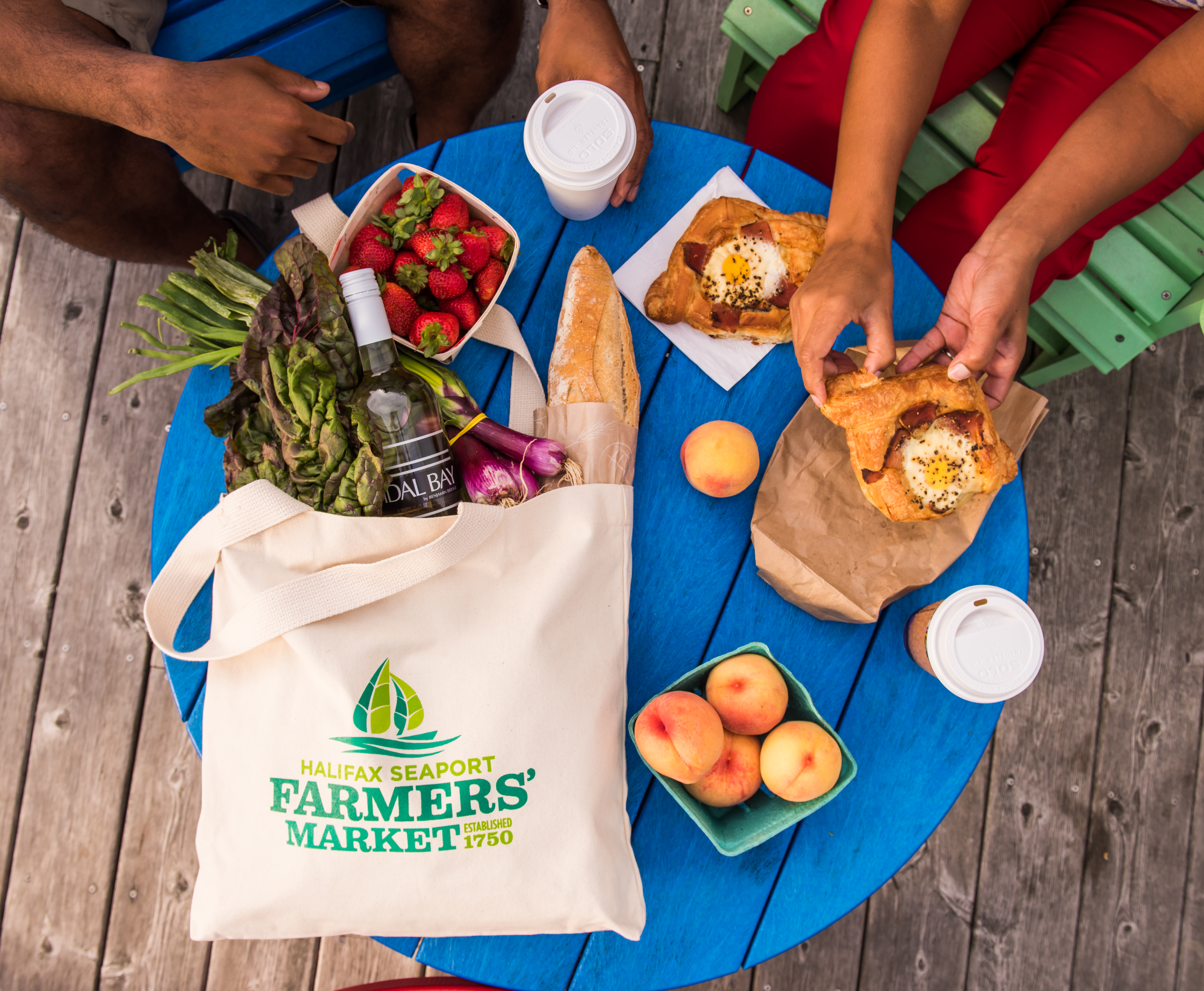Flat lay shot of fruit boxes, pastries and a tote bag of treats from a farmers market