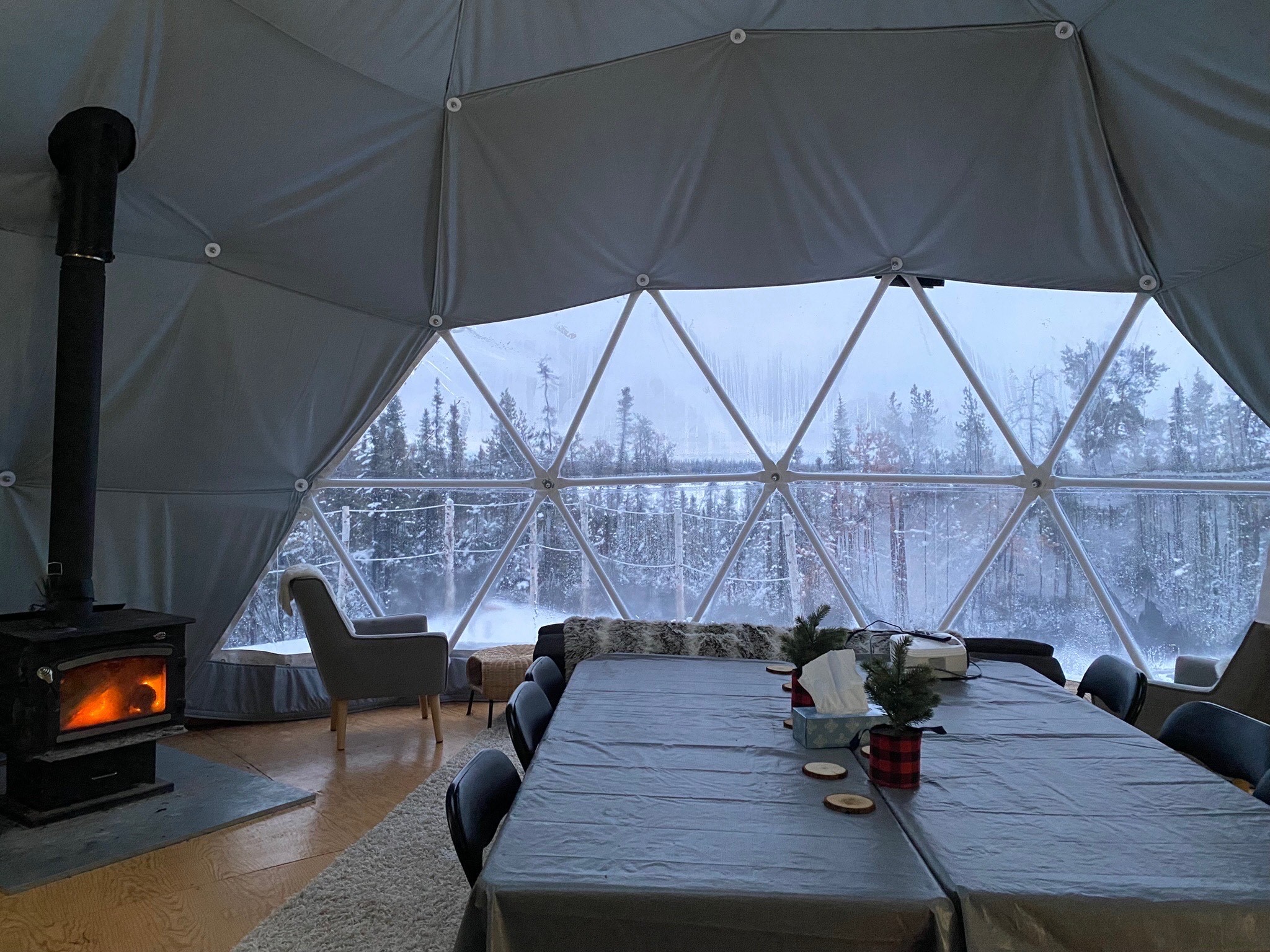 A dome with a table and chairs inside of it and snow outside