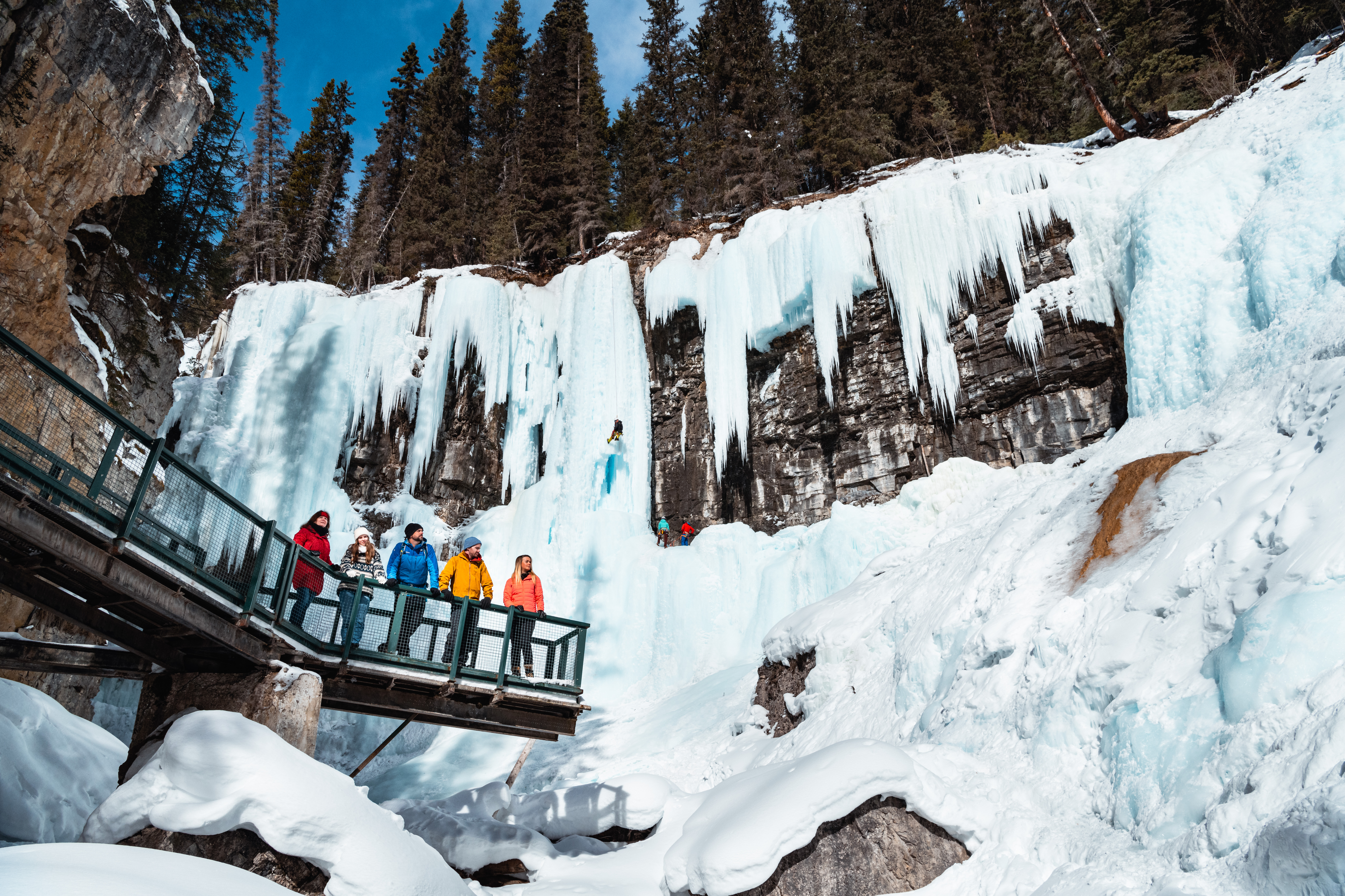 Small group standing on a viewing platform in the icy Johnston Canyon