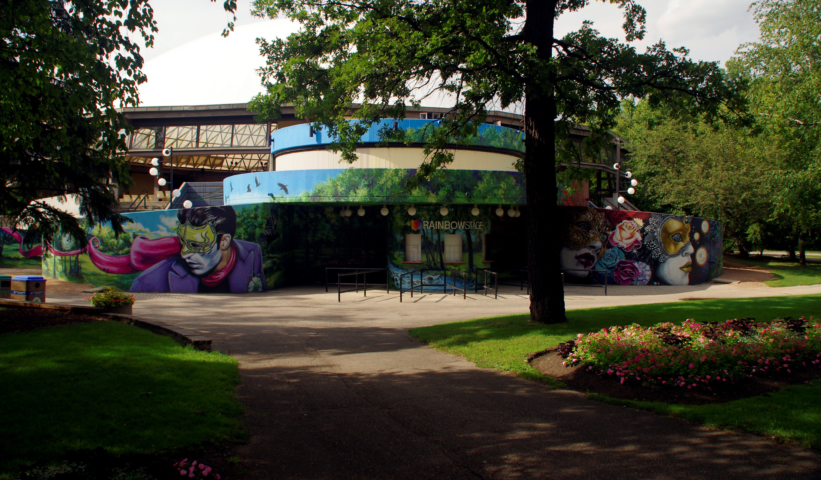 Park pathway leading to the entrance of an outdoor stage