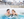 A couple sitting in an outdoor spa pool with views of snow-covered Montreal behind them