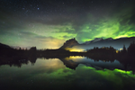 Colours of the Aurora Borealis reflected in a lake near a mountain in Banff 