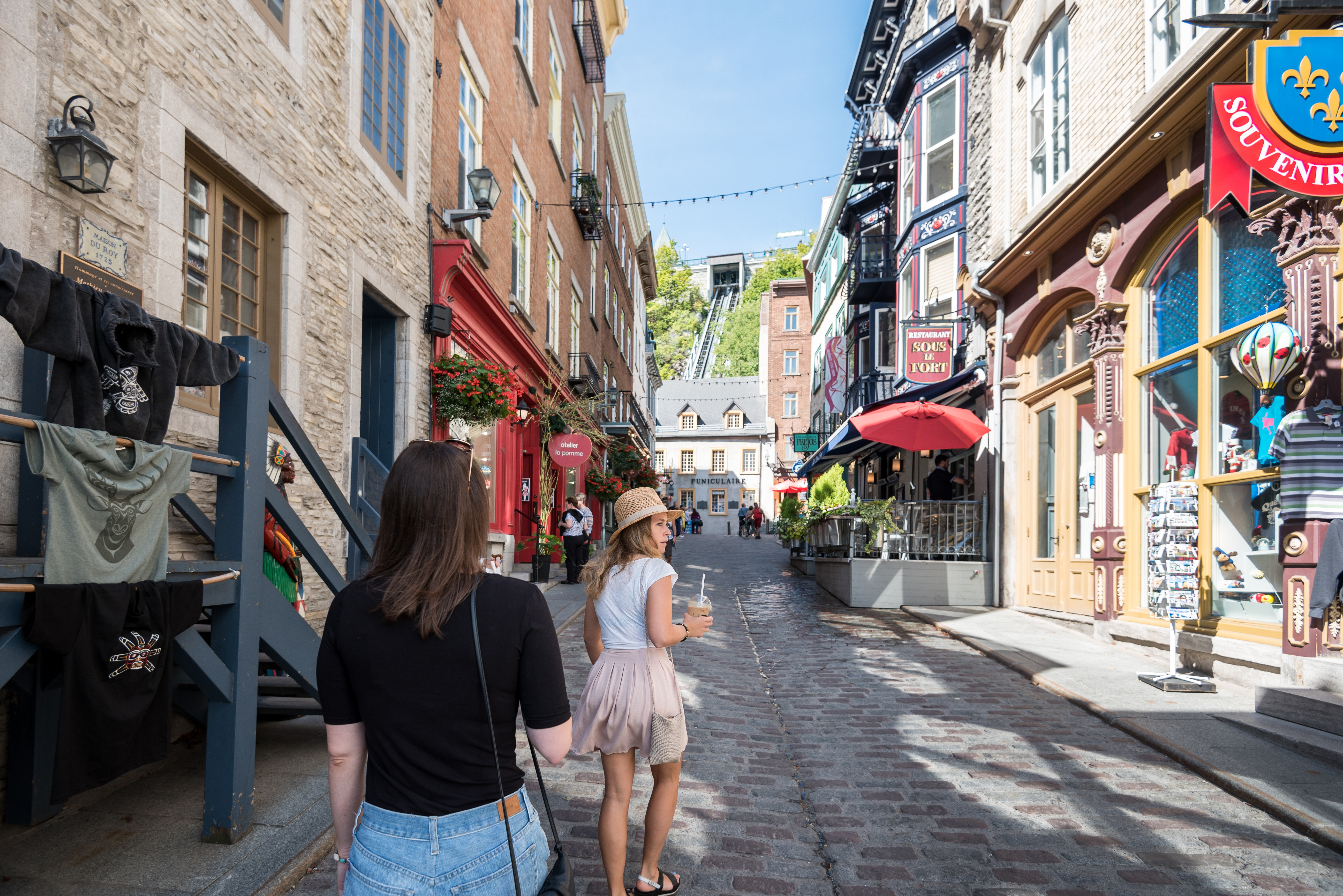 Two women walking past souvenir shops and small cafes in old Quebec City 