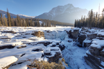 Athabasca Falls in Jasper National Park covered in snow with mountains in the background