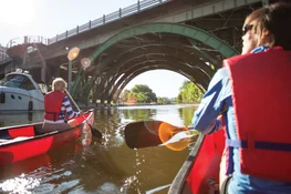 Two people canoe under the Laurier Avenue Bridge in Ottawa