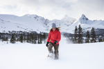 Person snowshoeing while wearing a red winter coat, ski pants and a hat