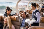 Onboard host serves wine to couple in the GoldLeaf dome