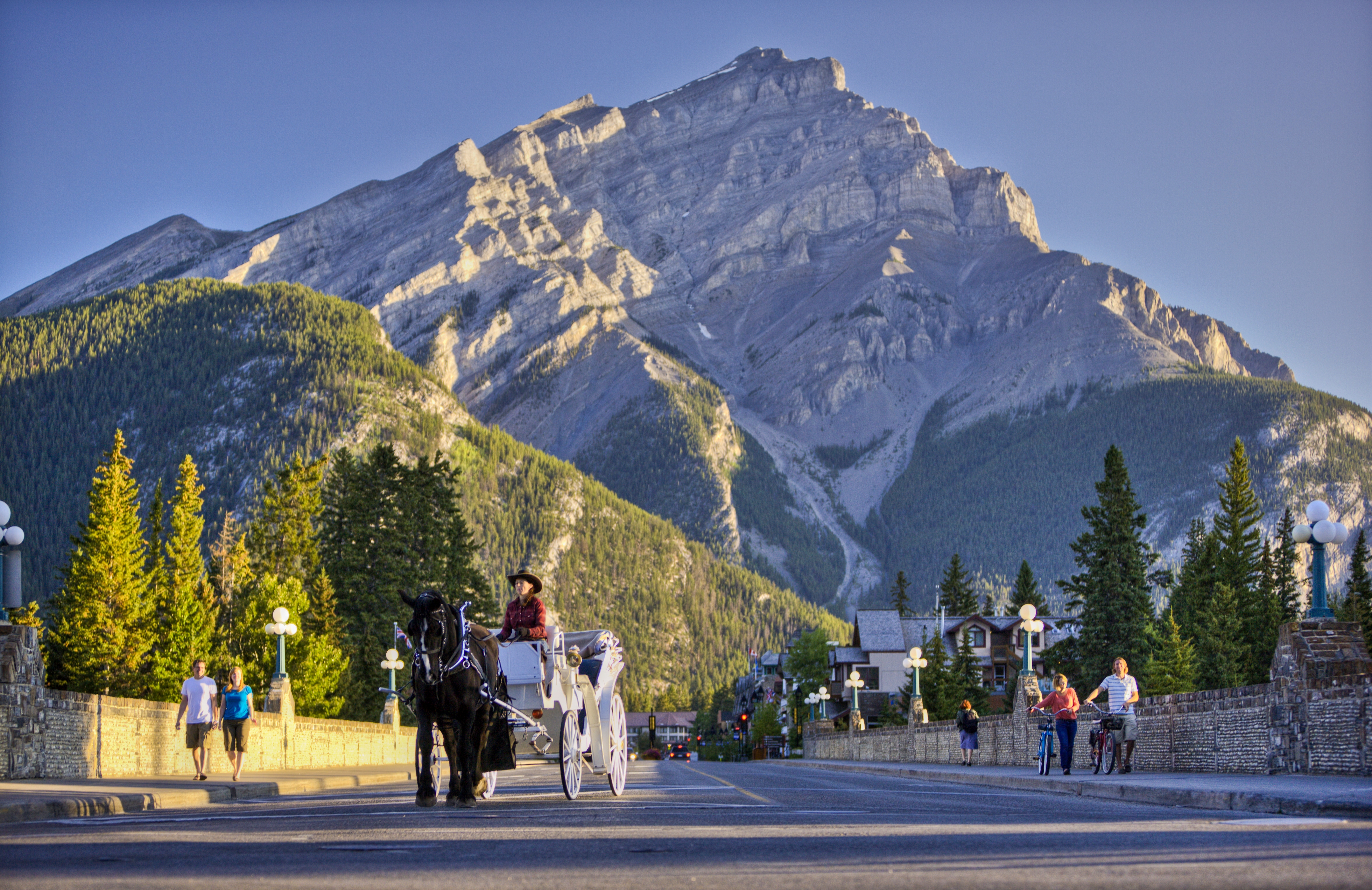 A horse and carriage going down Banff Avenue with towering mountains behind