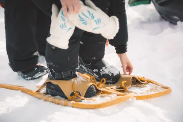 Person putting on old fashioned snow shoes