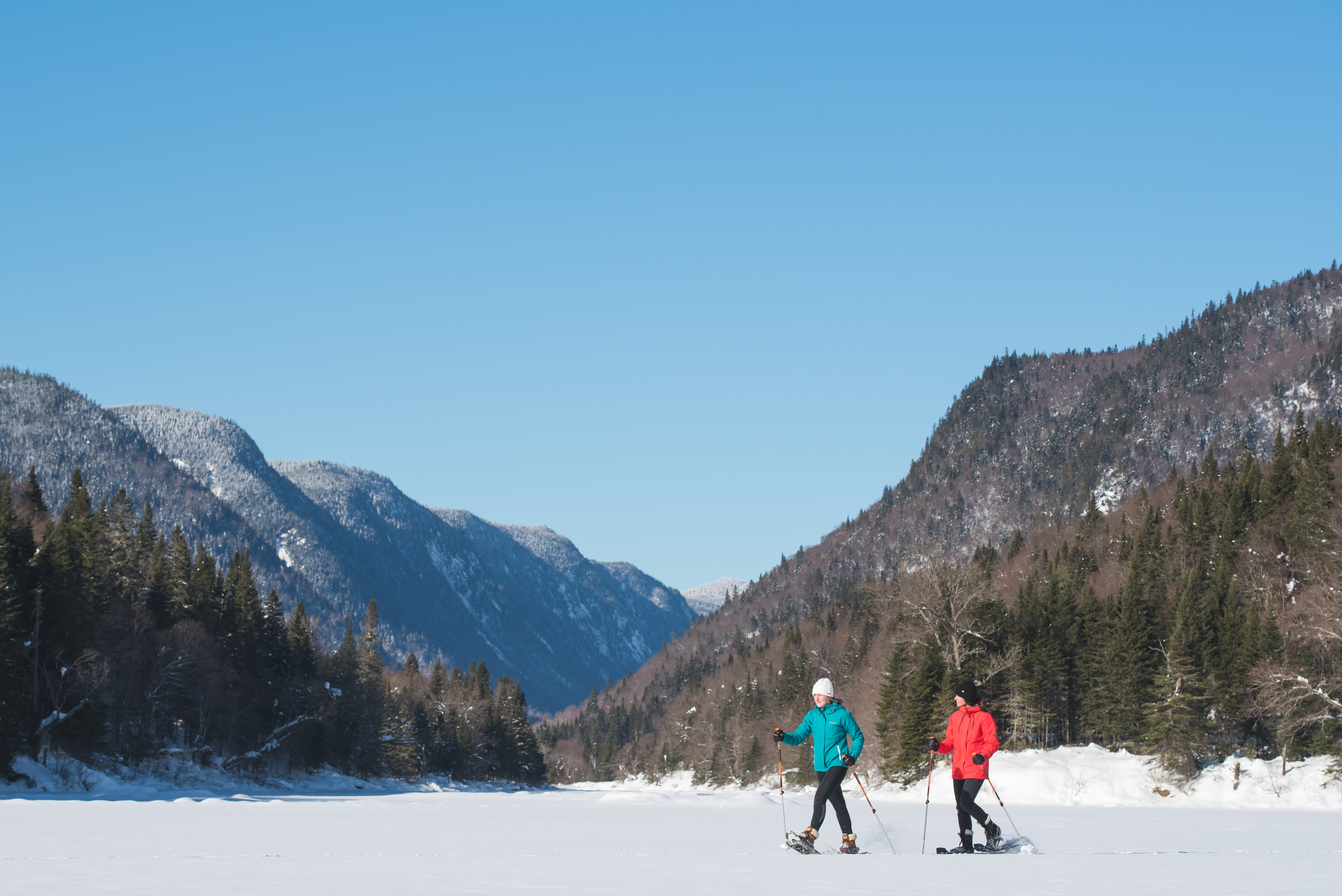 Two people snowshoe on trail located in Quebec's Jacques-Cartier National Park glacial valley