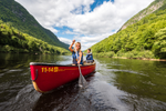Two people in a red canoe paddle on a lake in Quebec 