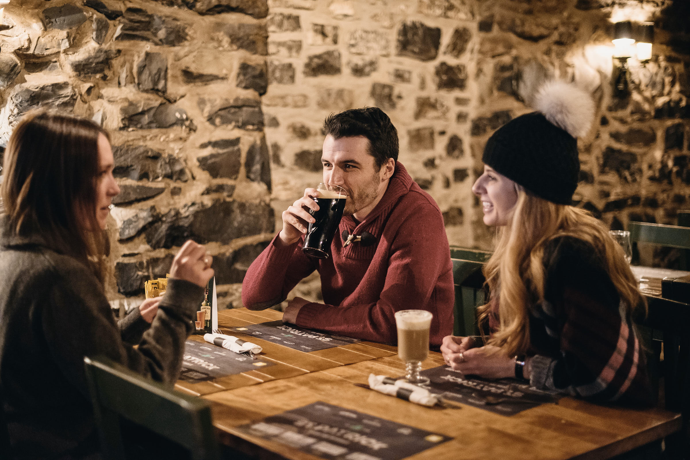 Friends enjoy a drink at an Irish pub with stone walls