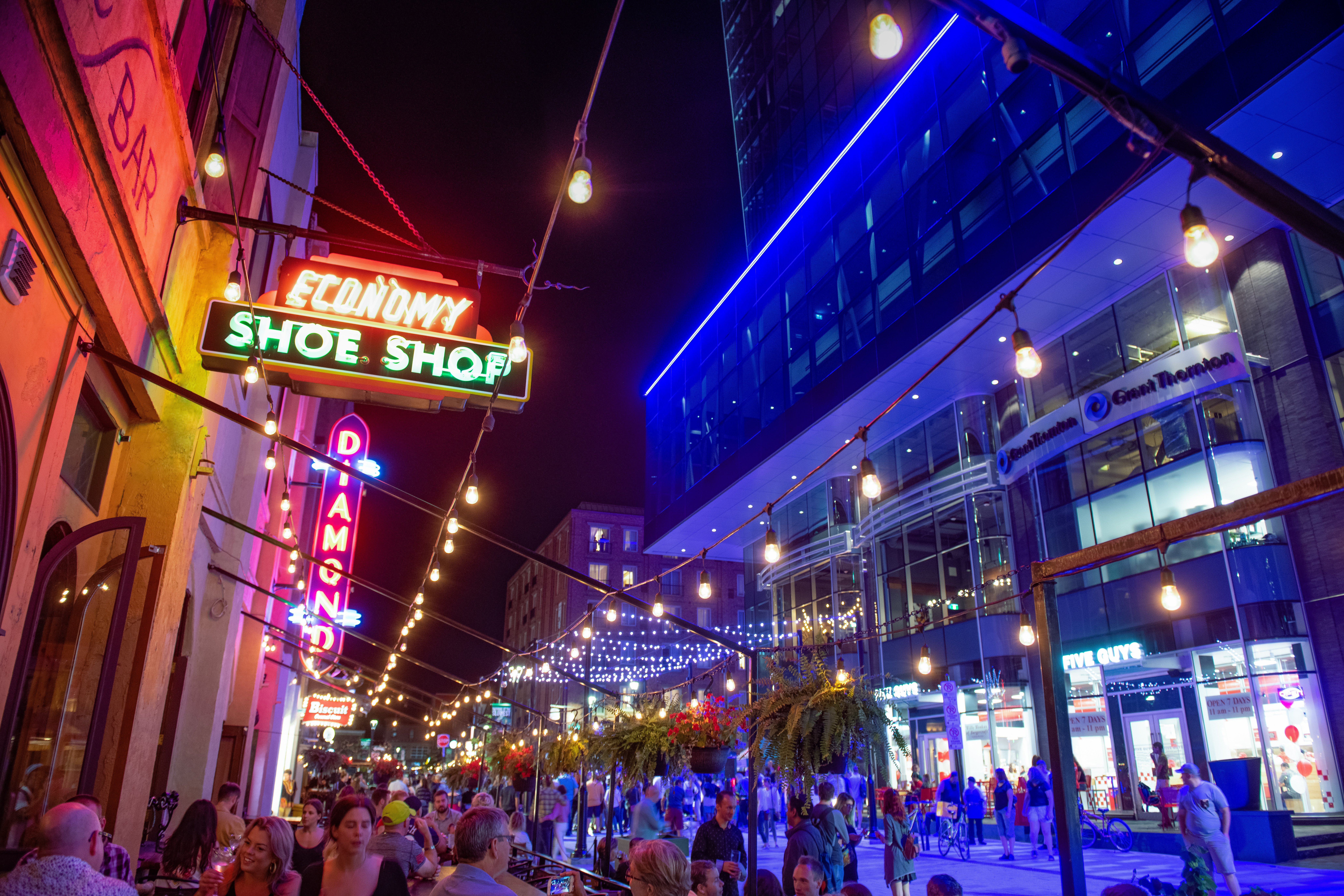 People sit in bar's outdoor terrace on colourful and glowing Argyle Street in the evening