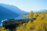 VIA Rail train travels along scenic passage with vivid fall foliage and lake in the Canadian Rockies