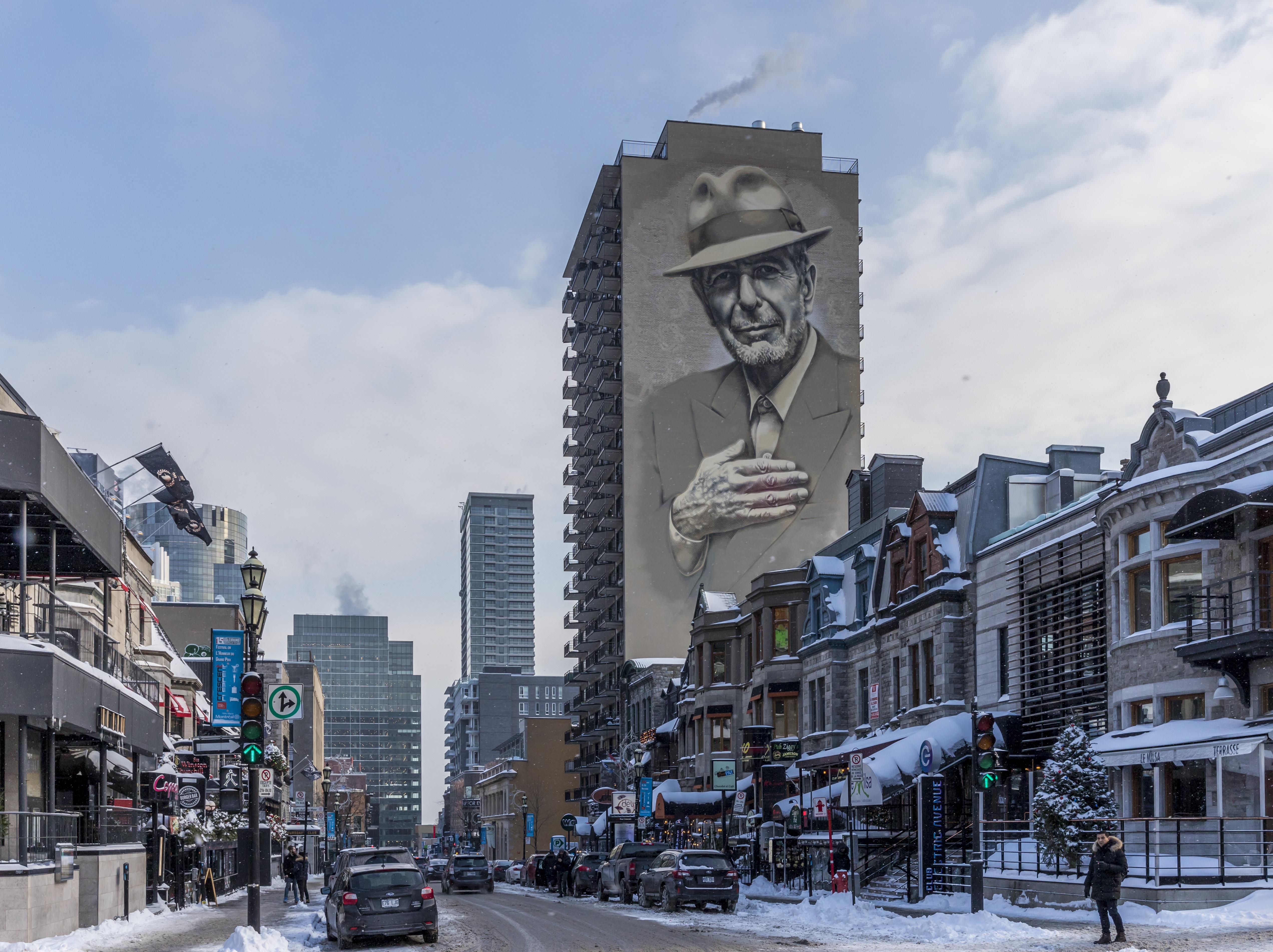 View down a snowy street in Montreal with the Leonard Cohen mural on a high rise building
