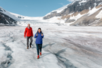A couple visit icefield and walk among glacier on a bright day 