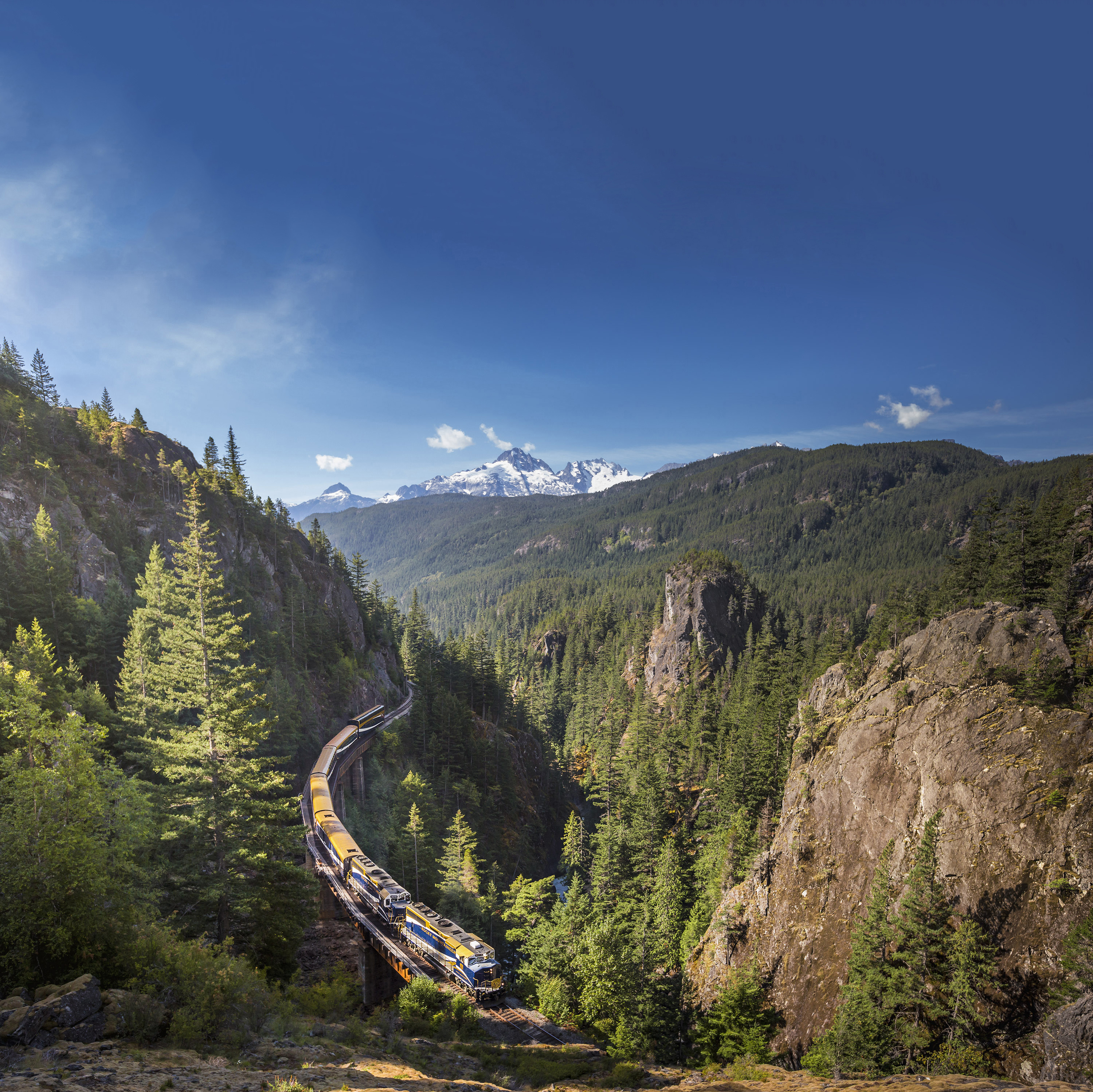 Rocky Mountaineer train travels through mountainous landscape and vast forests during journey