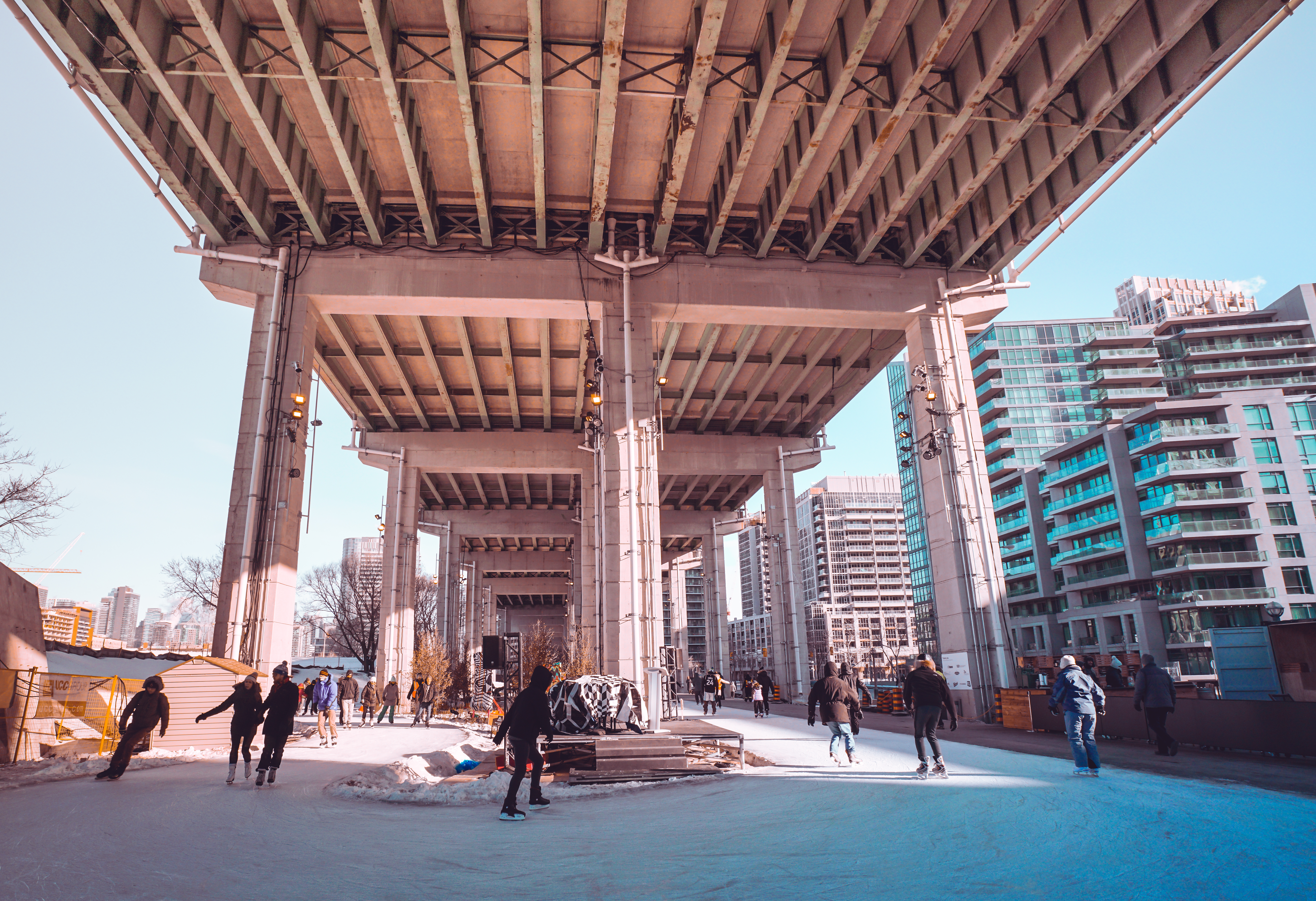People ice skating under a bridge in Toronto during the day