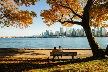 A couple sits on a bench looking out at Coal Harbour in Vancouver