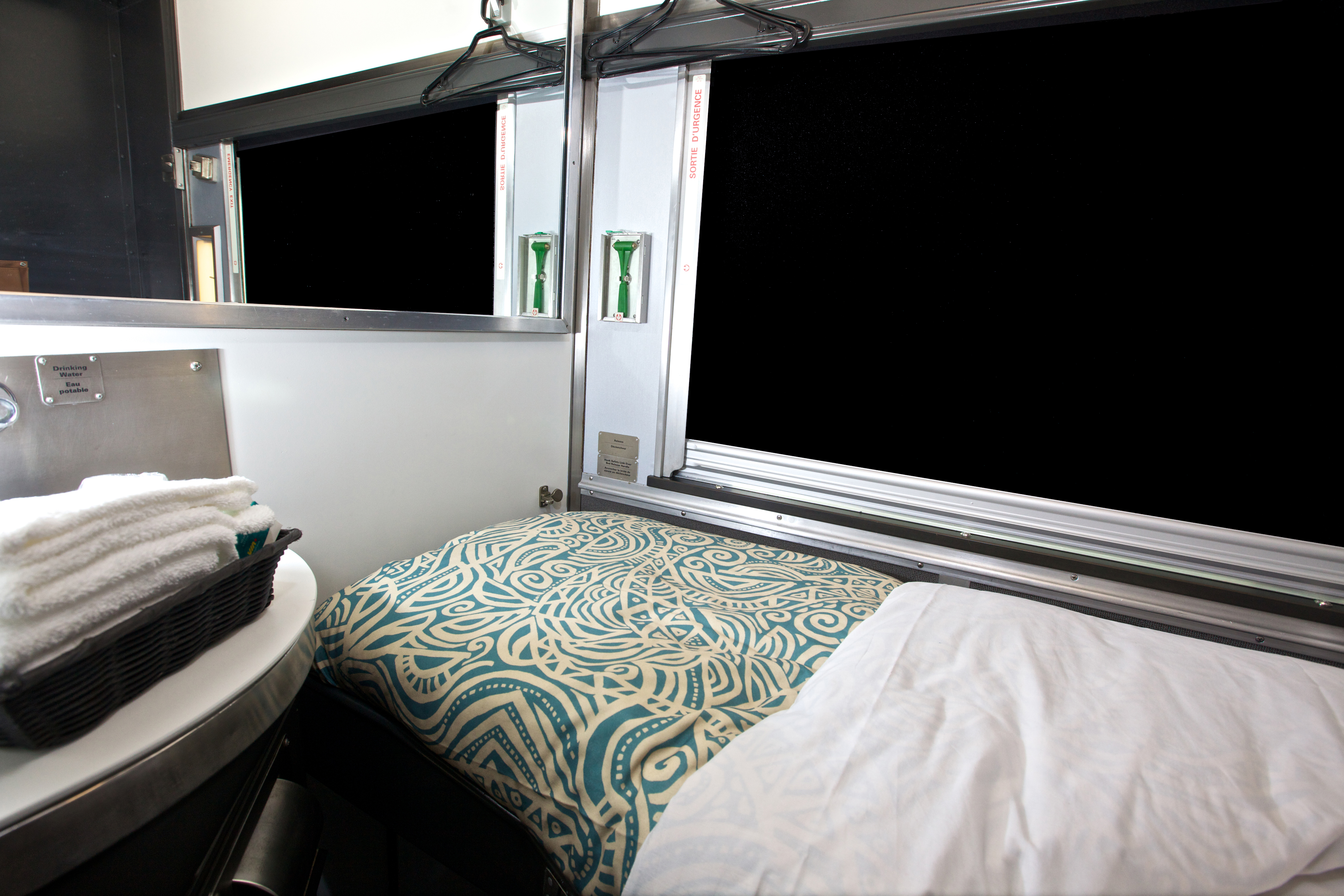 VIA Rail Canadian Train cabin for one, setup with a bed beside the window with the blinds down.