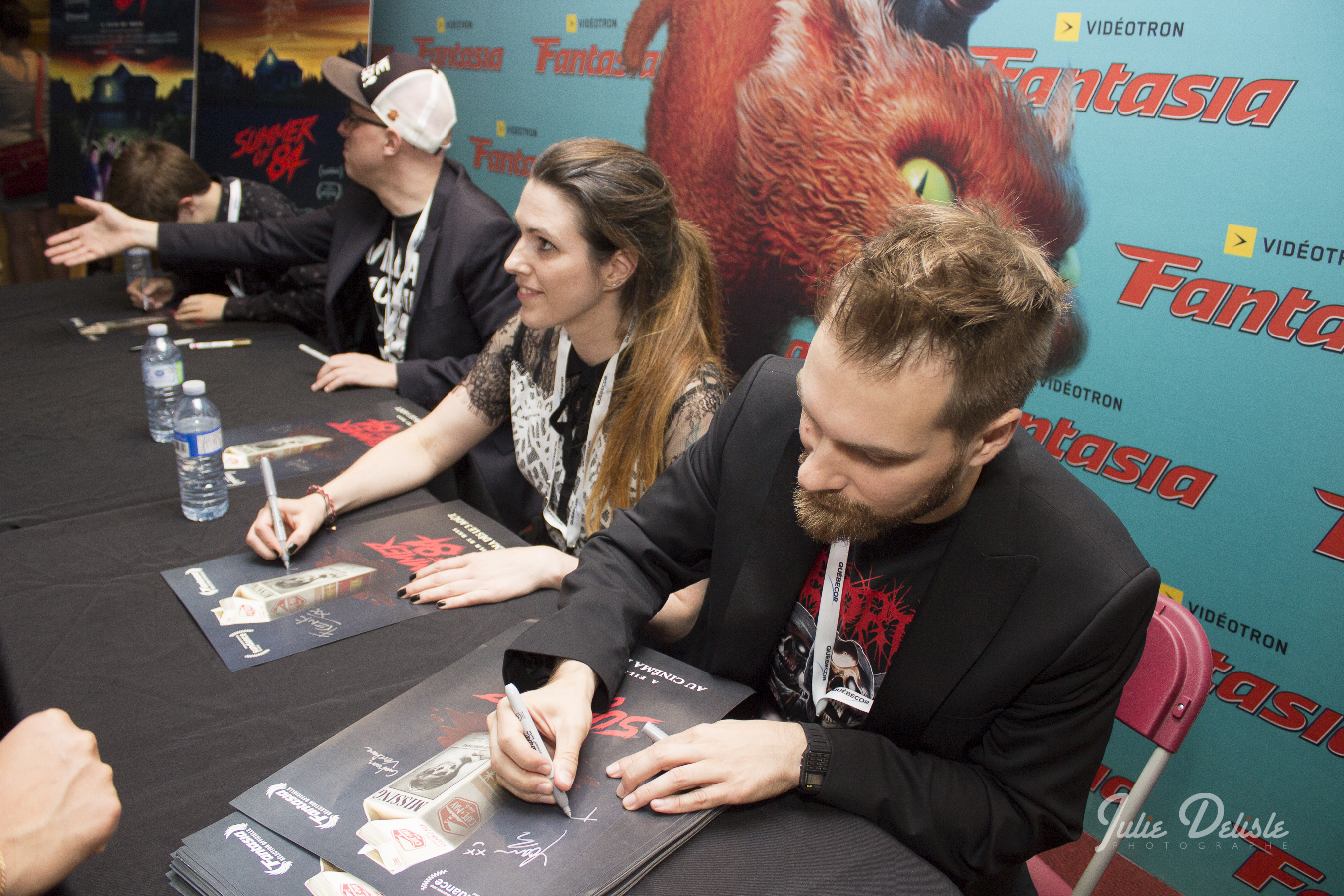 Film artists sign posters at a table during the Fantasia International Film Festival