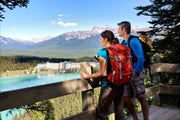 Couple wearing backpacks looking over the viewpoint at Lake Louise
