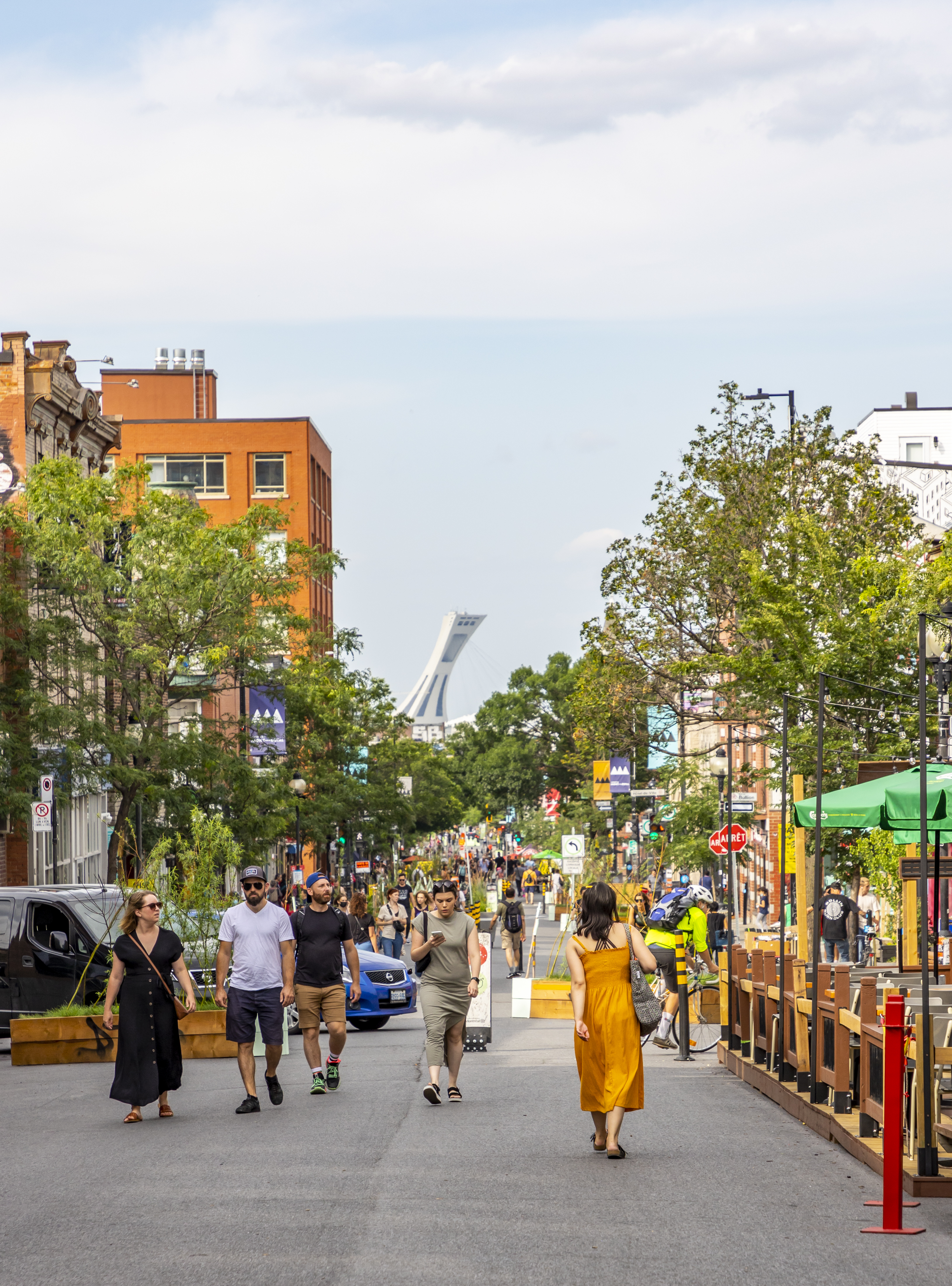 People walking down a busy road in Montreal during summer