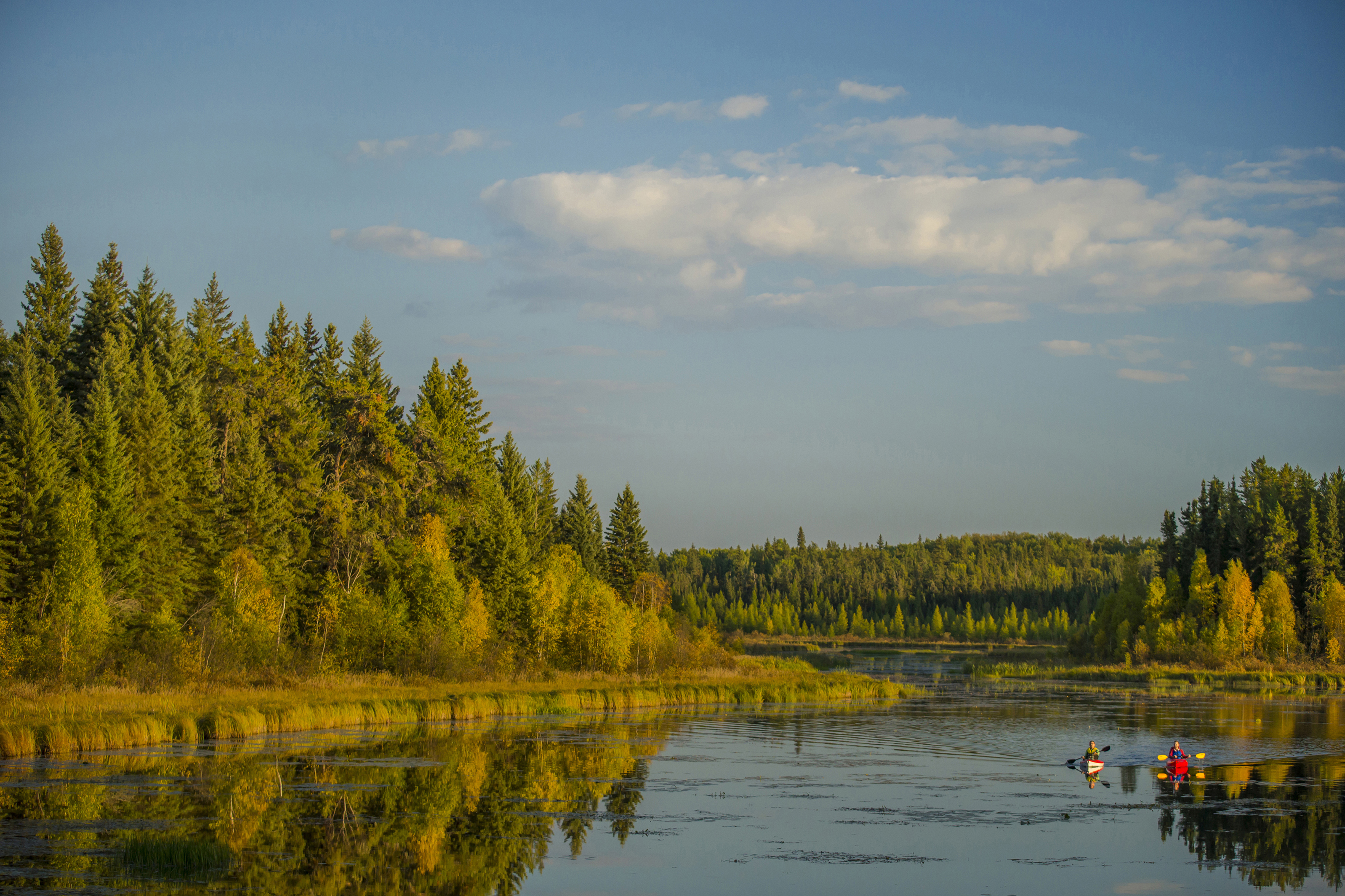 Kayakers paddle on a lake in Prince Albert National Park on a sunny day