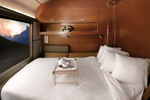 Lower double bed with four pillows facing the window in a VIA Rail Prestige cabin