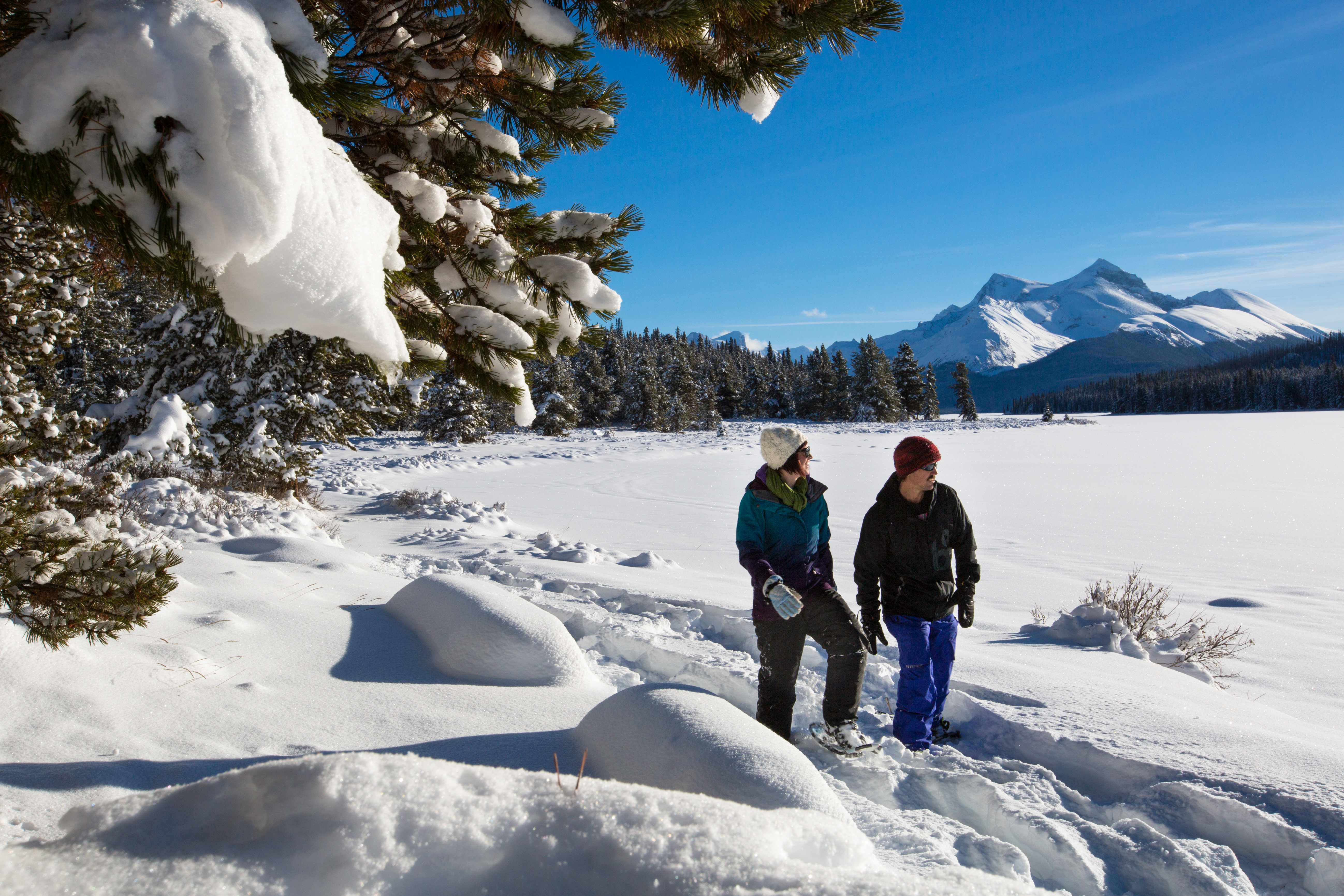A couple snowshoeing beside snow-covered Maligne Lake