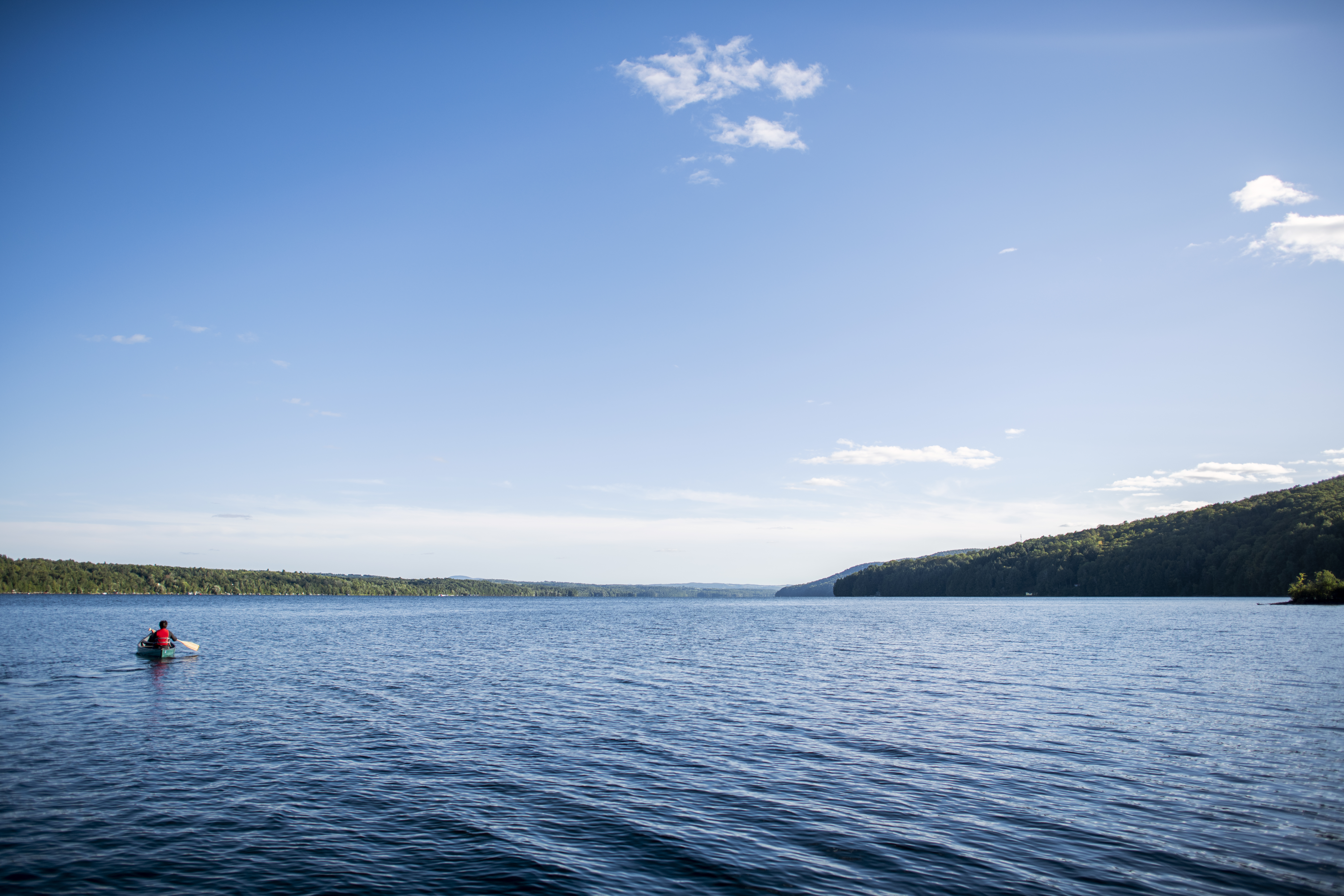 Person paddles on board in calm waters in Lake Memphremagog in the American state of Vermont and Magog, Quebec