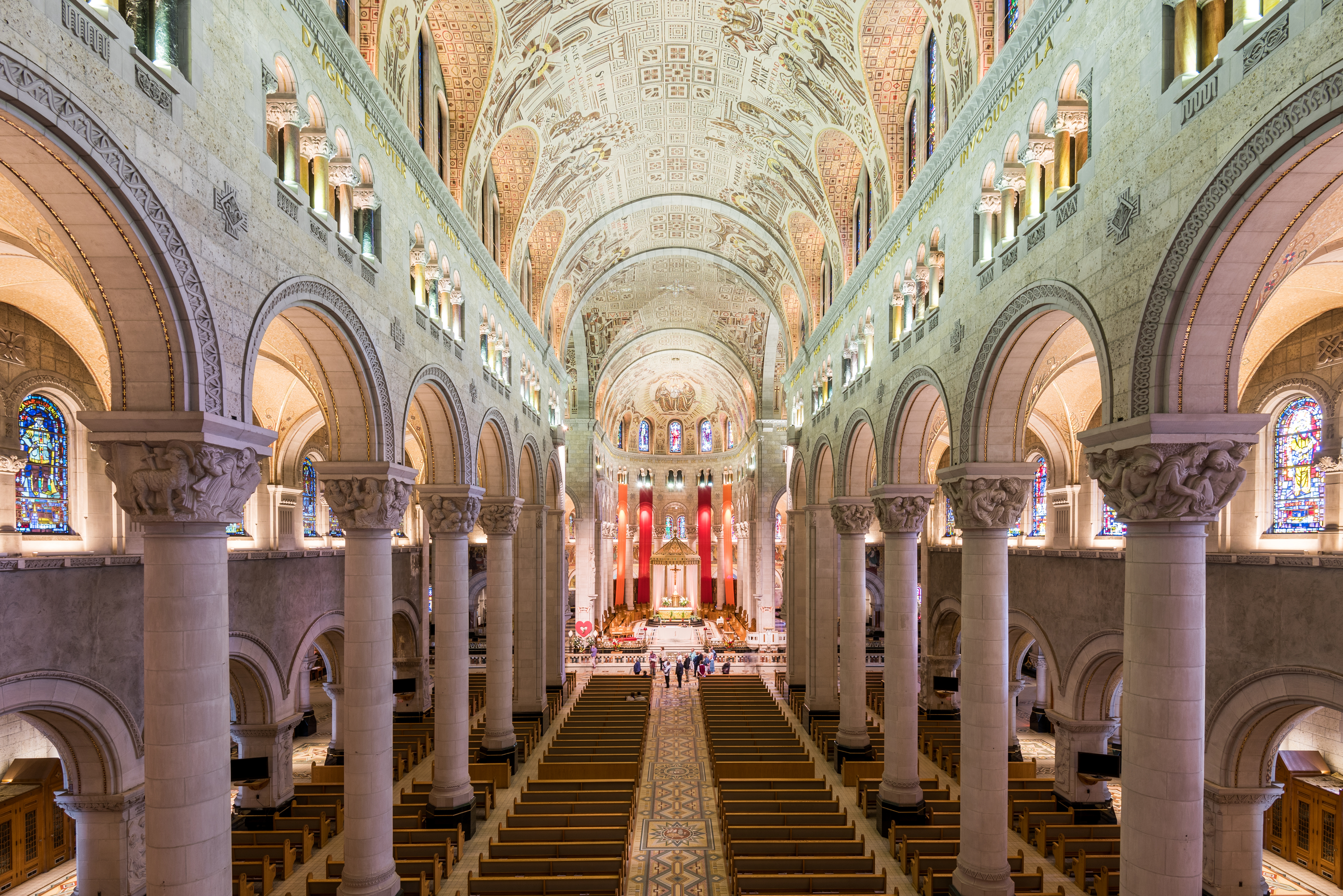 Columns, archways, stain-glass windows and intricate ceiling inside a basilica 