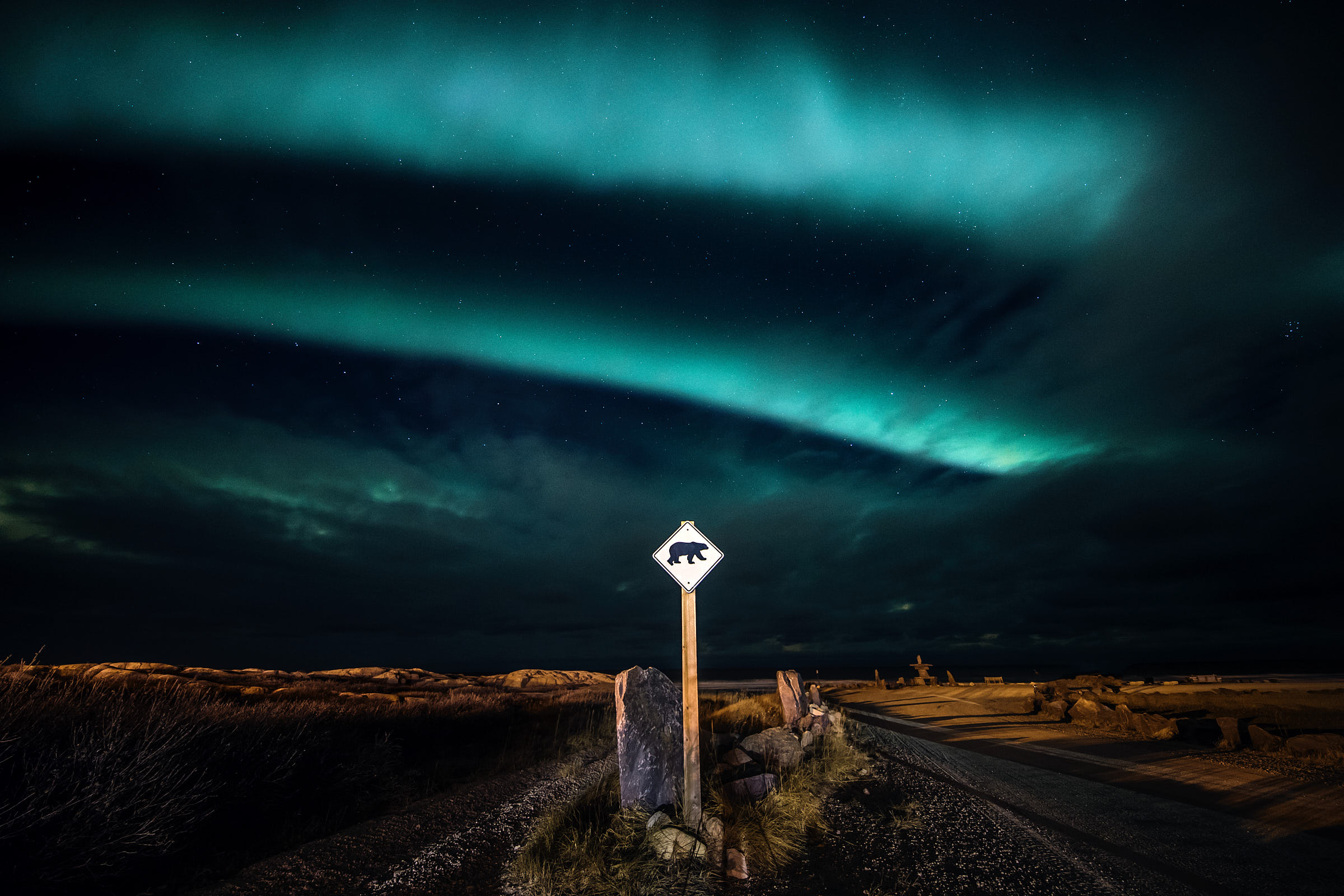 Blue shades of the Northern Lights in the sky above a bear road sign in Churchill 