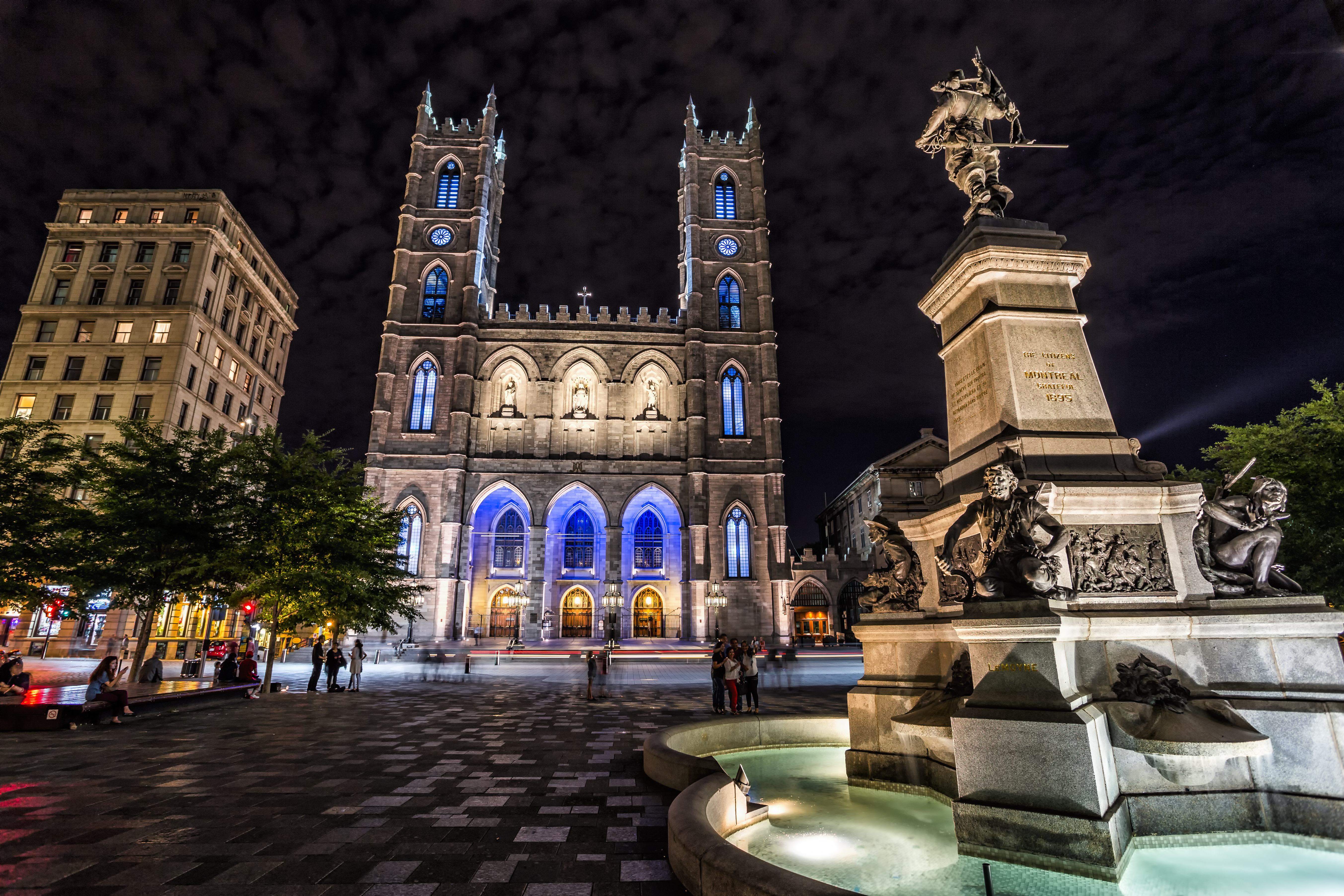 Place d'Armes of Montreal with Notre Dame basilica, lit up at night with blue lights
