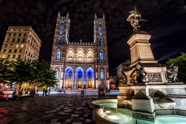 Place d'Armes of Montreal with Notre Dame basilica, lit up at night with blue lights