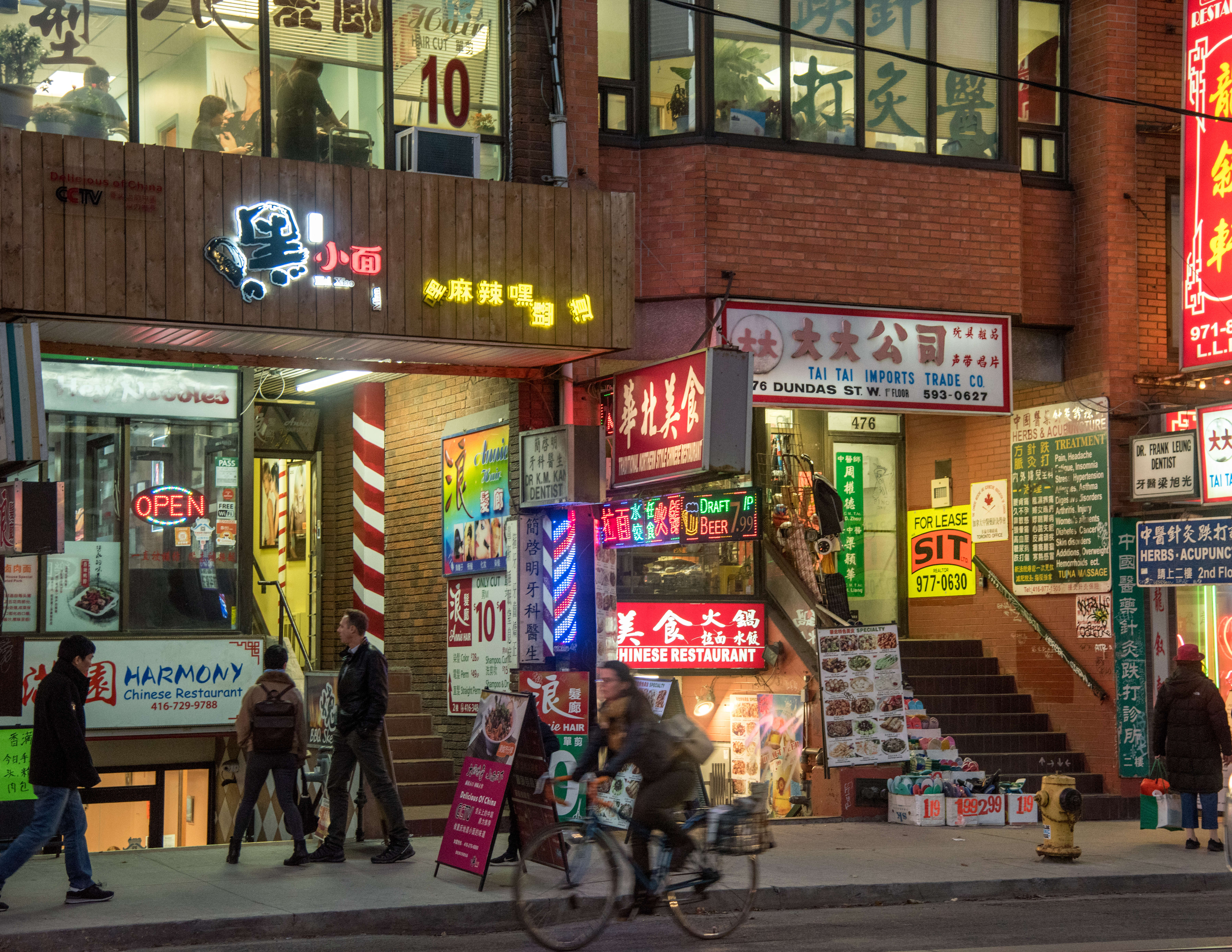 People walking and cycling past shops in Toronto's Chinatown