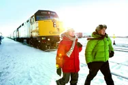 A couple in winter clothing walks by a VIA rail train