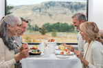 In Rocky Mountaineer’s GoldLeaf service, two couples eat breakfast together next to a large window