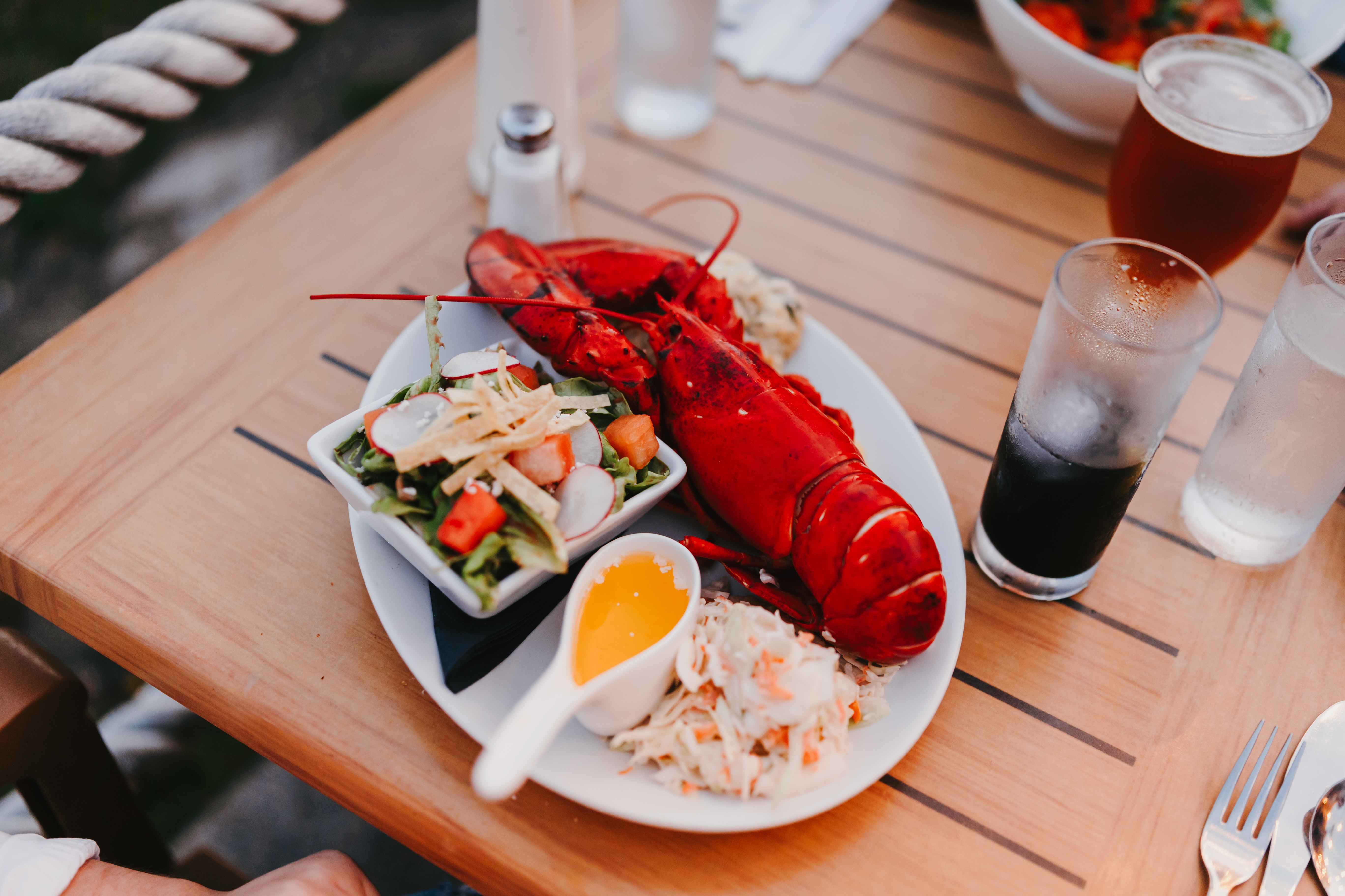 Red lobster served with a side of salad set on table and a drink in restaurant in Alma, New Brunswick
