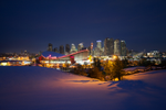 Exterior view of a snowy field, Scotiabank Saddledome, and Calgary city skyline at night