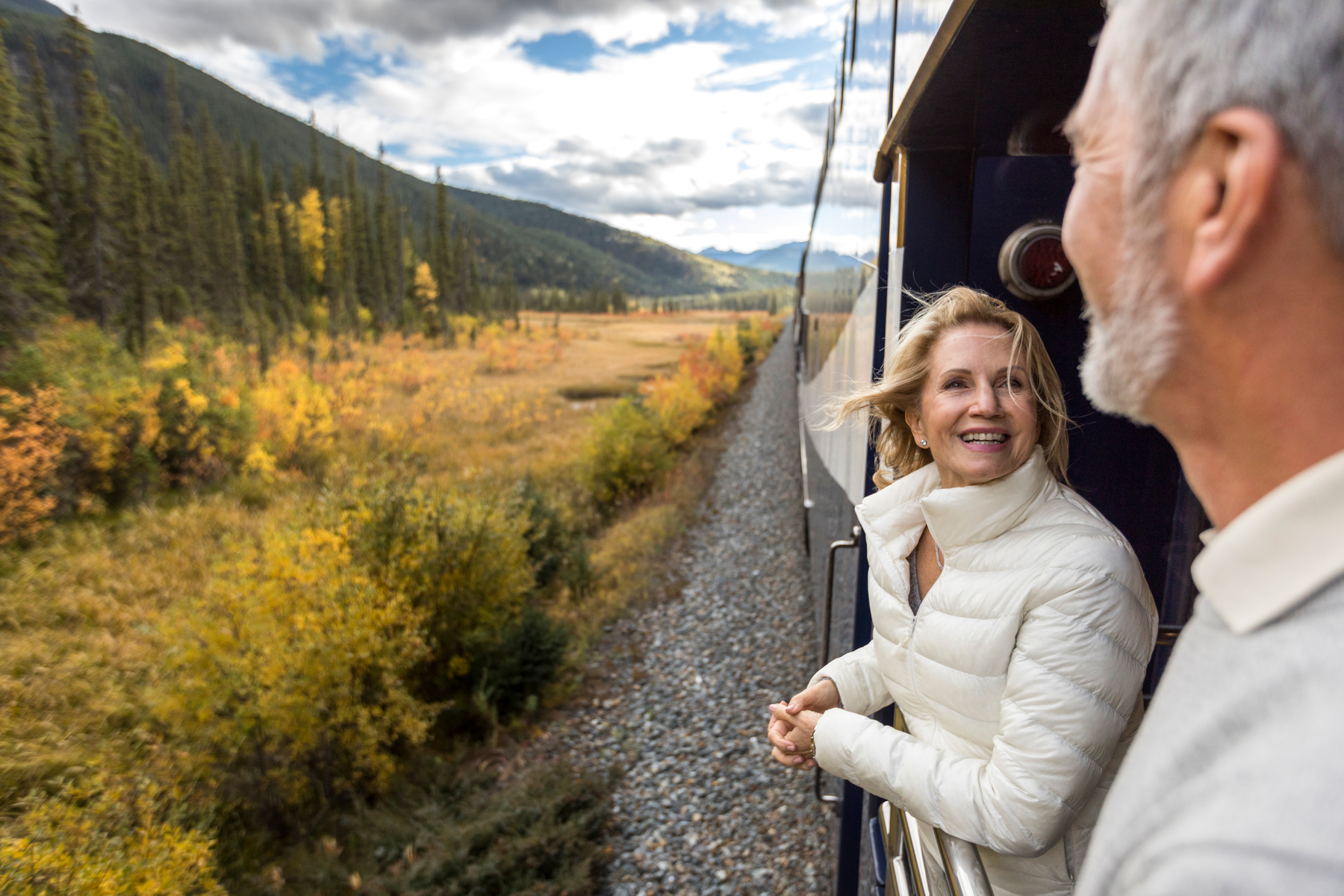 Couple enjoys the view from the GoldLeaf service outdoor viewing platform on the Rocky Mountaineer Train.