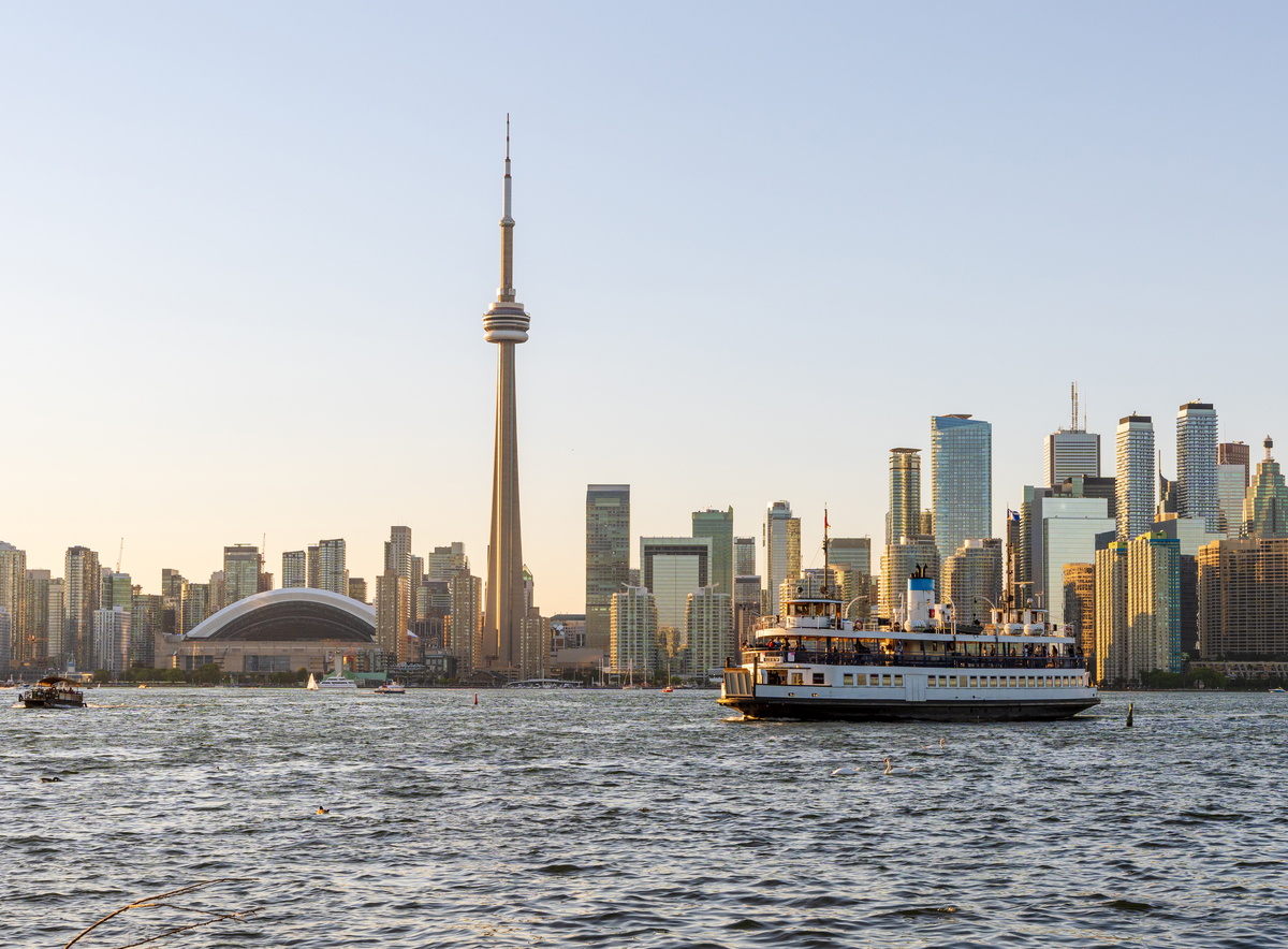 View of Toronto Island Ferry passing by city skyline at sunset