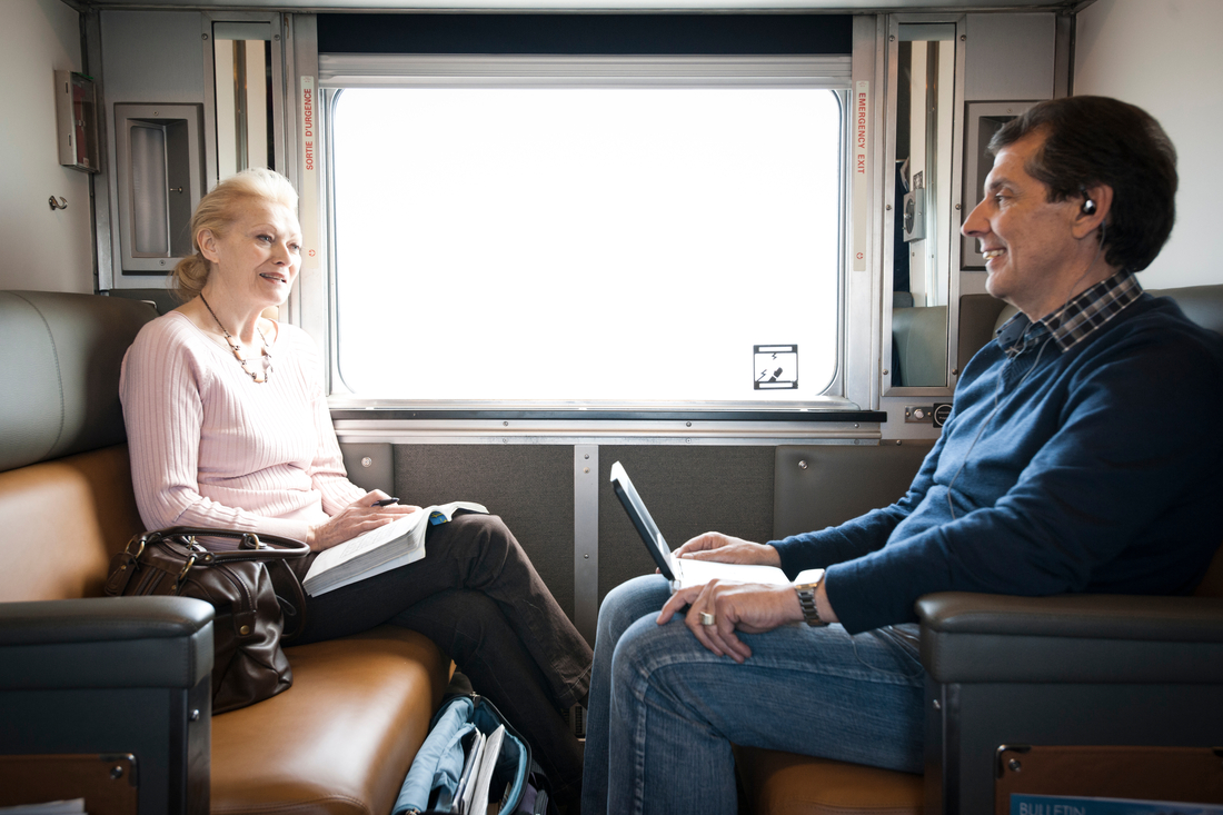 Two passengers enjoying the Sleeper Plus service level, chatting at their semi-private berth during a VIA Rail journey.