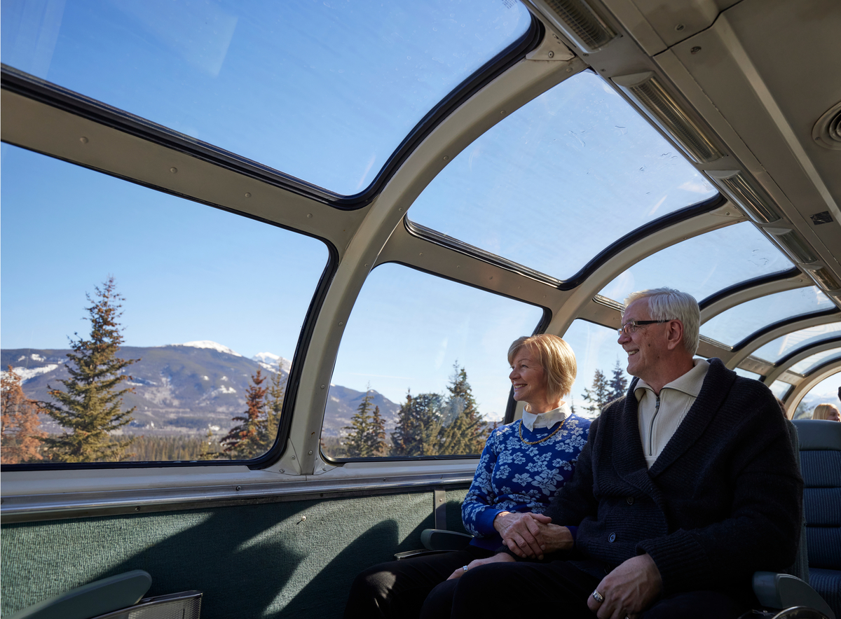 Couple enjoying view of Rockies from the domed viewing area on VIA Rail Canadian train