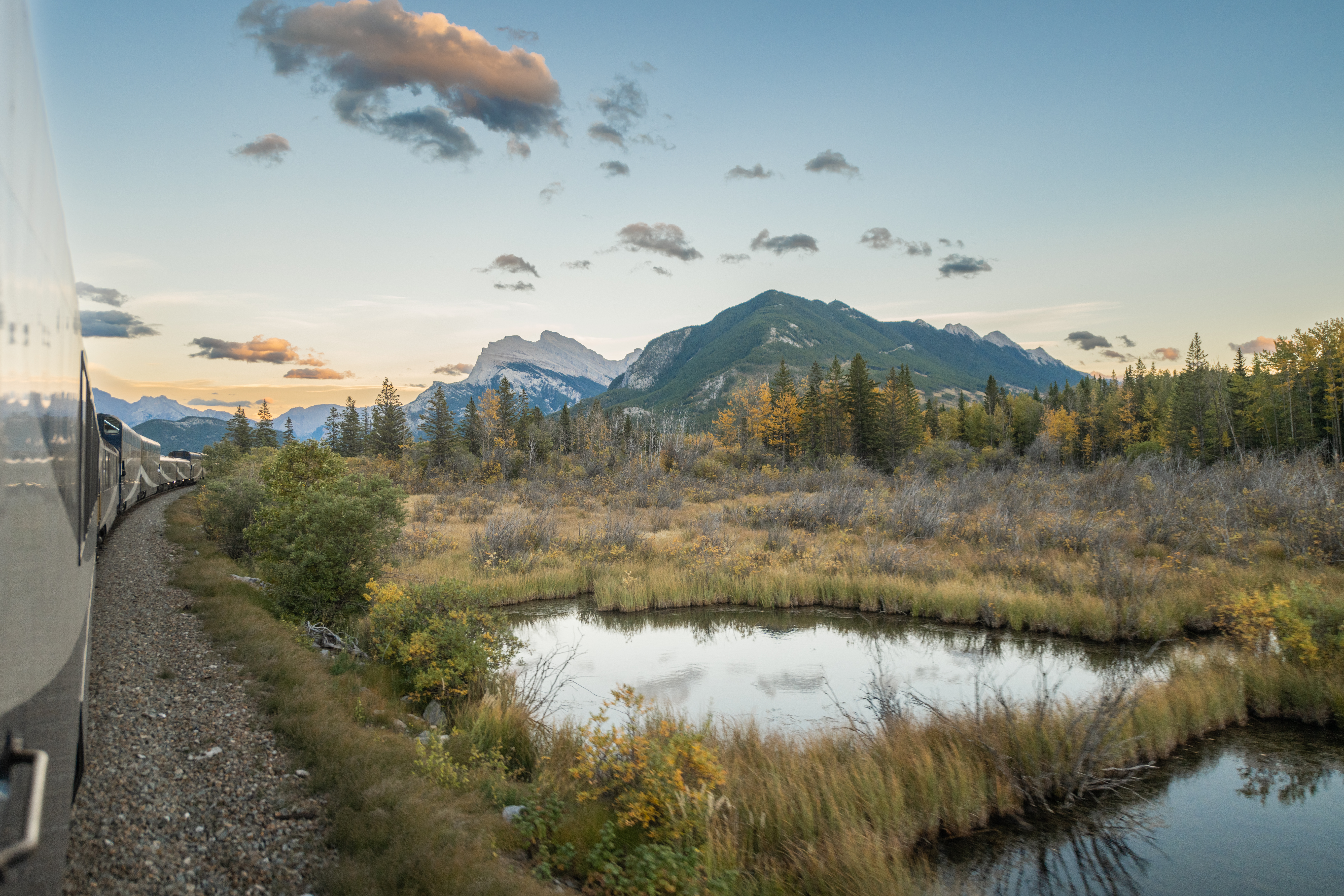 Rocky Mountaineer train goes past lake and mountain scenery in the Canadian Rockies