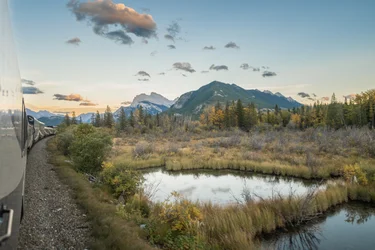 Rocky Mountaineer train goes past lake and mountain scenery in the Canadian Rockies