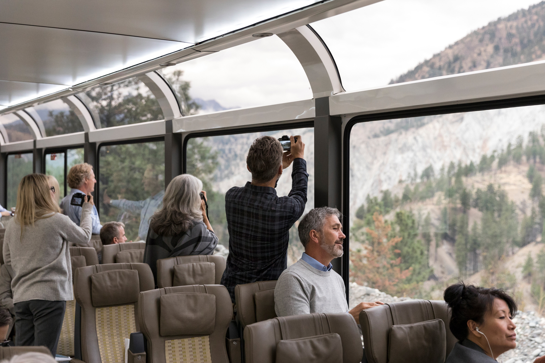 Guests taking photos from inside the SilverLeaf coach on the Rocky Mountaineer Vancouver to Banff train