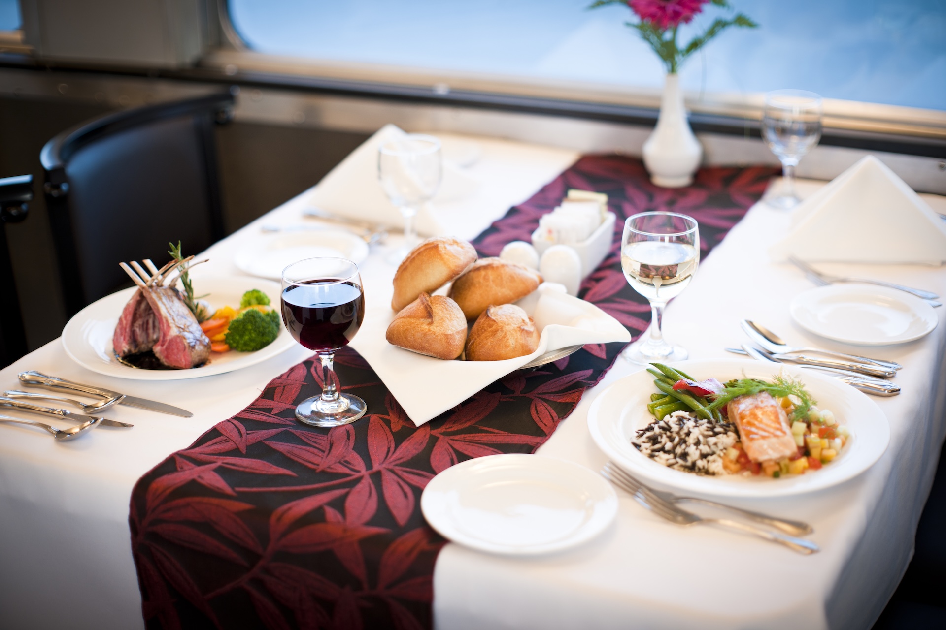 Canadian Train dining car table with two entrees, wine and rolls in the middle.
