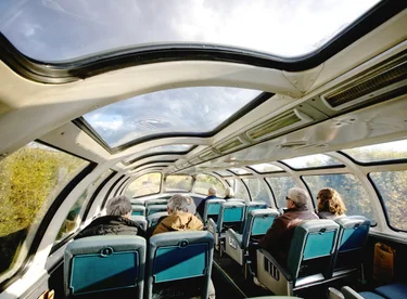 The Skyline Car upper-level lounge with seating under glass-domed windows on the VIA Rail train